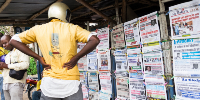 Un conducteur de taxi-moto consulte des urnes de journaux à Cotonou