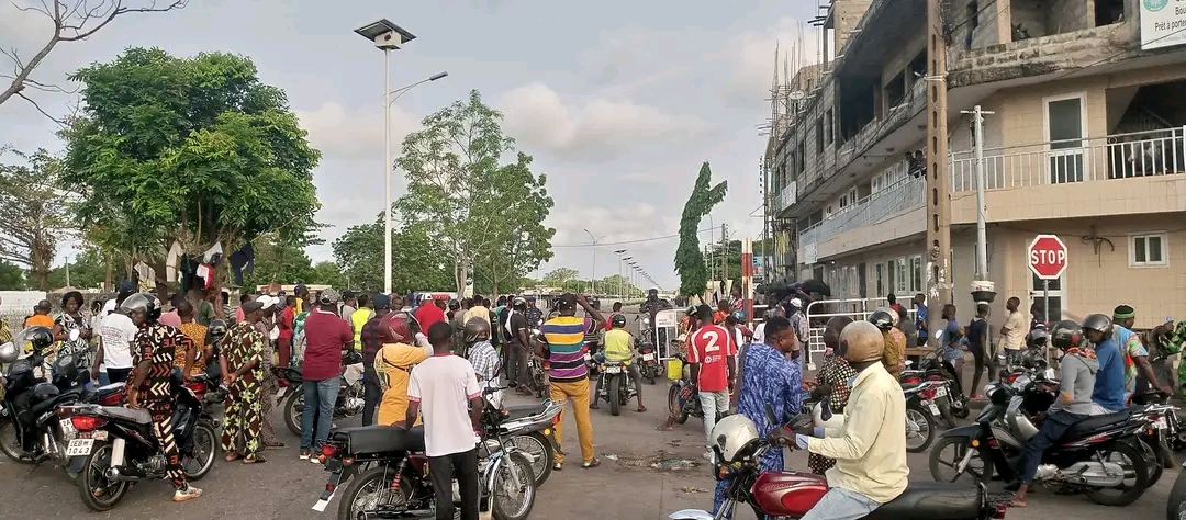 Des populations attendent devant une barricade de la police républicaine non loin de la Bourse du travail à Cotonou. ©